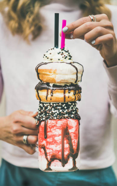 meisje koude aardbei donut freakshake bedrijf in handen - freakshake fruit stockfoto's en -beelden