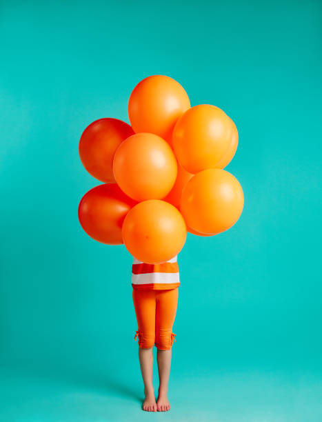 girl holding orange balloons in front - laranja cores imagens e fotografias de stock