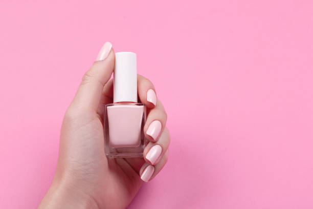 girl holds nail polish with a beautiful manicure stock photo
