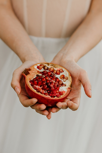 Russia, Nizhny Novgorod - June 27, 2019: park, a girl in a wedding dress holds a fresh half of a pomegranate