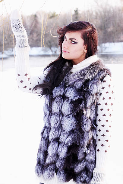 Young beautiful girl in a fur vest catches snow