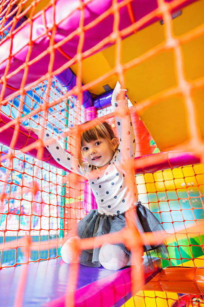 Girl in a playroom. Cute little girl playing in an indoor playground and looking at the camera.   indoor playground stock pictures, royalty-free photos & images