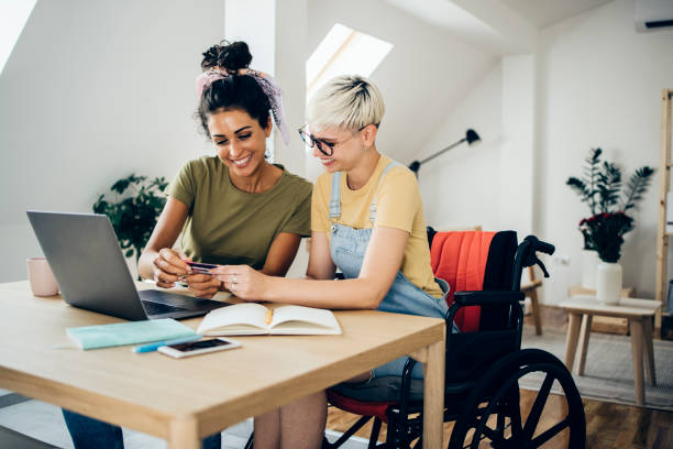 Girl in a wheelchair and her best friend shopping online stock photo