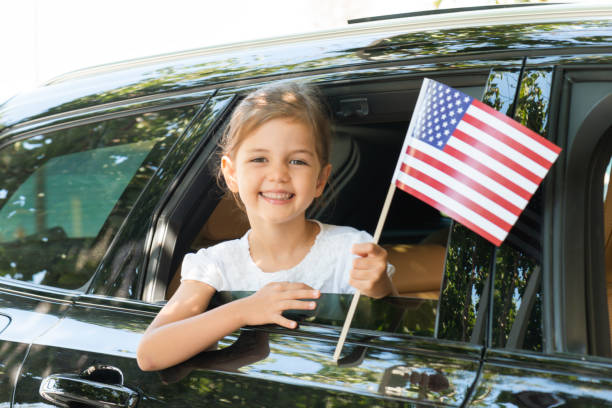 девушка в машине держит американский флаг - july 4 стоковые фото и изображения