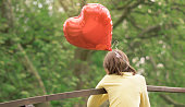 istock Girl in love, holding heart shaped balloon 1209454109