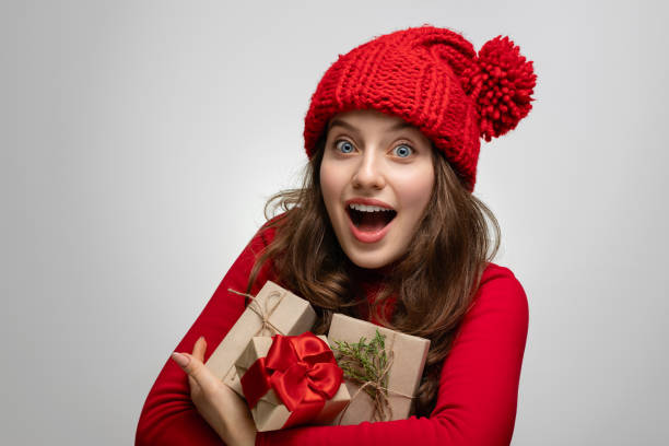 girl in red with an armful of gifts, joy on her face - woman holding a christmas gift imagens e fotografias de stock