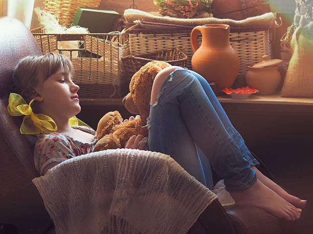 Girl in the sun Girl teenager in the attic or in the pantry sits in an old chair with a toy. Lots of sun, the sun's rays. The girl speaks with a toy. Many different items teddy ray stock pictures, royalty-free photos & images