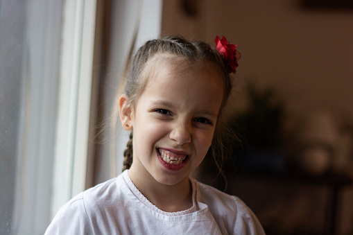 Smiling girl in traditional Serbian costumes standing at home and looking at camera