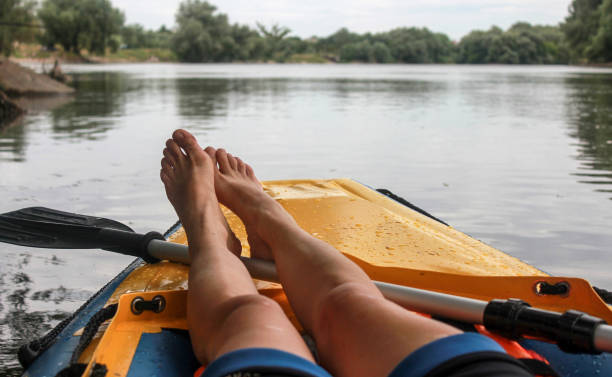 Girl is relaxation on boat  the river. Close-up of bare feet. POV stock photo