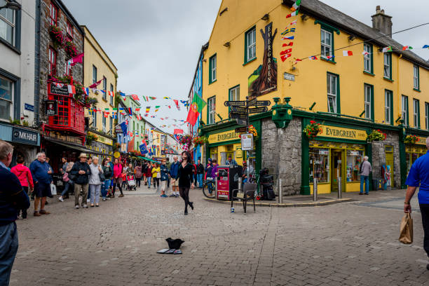 Girl is tap dancing in Galway Galway, Ireland - August 07, 2018: People walking along one of the main pedestrian streets in Galway. It is full of shops, pubs and restaurants. A girl is tap-dancing. galway stock pictures, royalty-free photos & images