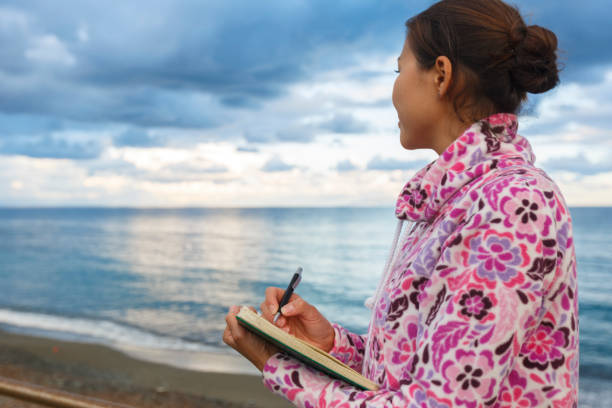 A girl is writing on a beach. Copywriter. Author. Literature. Creativity. Freelancer stock photo