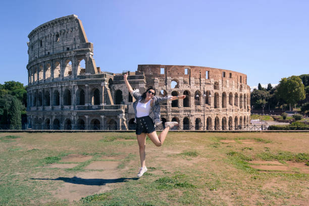girl jumping in front of the colosseum in Rome stock photo
