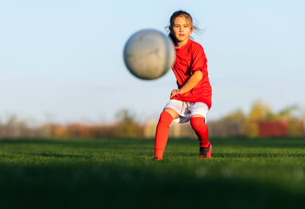 Girl kicks a soccer ball on a soccer field stock photo