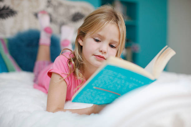 menina na cama a ler livro poedeiras - child reading imagens e fotografias de stock
