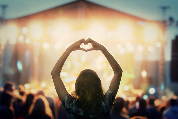 girl making a heart-shape symbol for her favorite band. - festival stockfoto's en -beelden