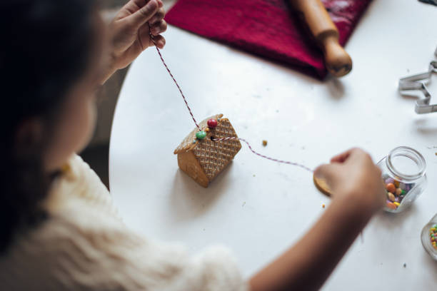 Girl making Christmas gingerbread house cookies stock photo