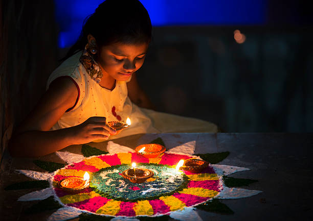 A Little girl making Rangoli and decorating with Oil lamps for Diwali celebration in India.
