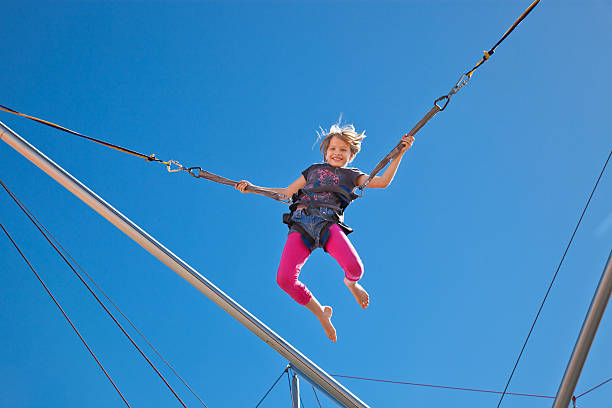 Girl Mid-Air in harness on Bungee Carnival Ride Amusement Park stock photo