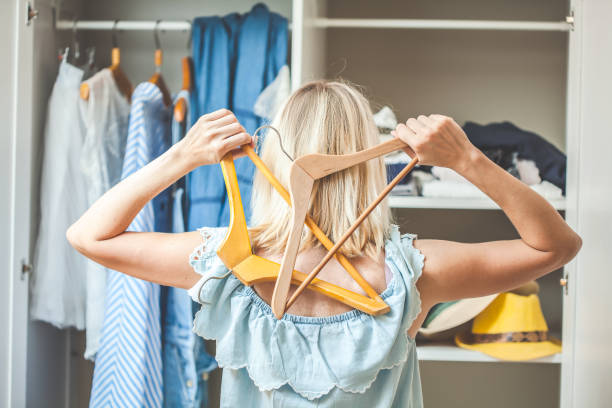 girl near a wardrobe with clothes can not choose what to wear. Heavy Choice Concept has nothing to wear stock photo
