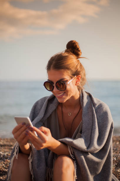 Girl on the beach using phone stock photo