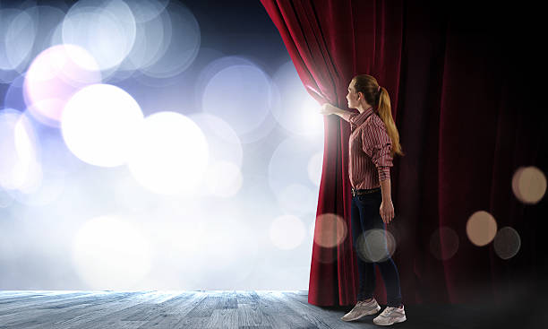Girl opening curtain Young woman in casual opening stage curtain actor stock pictures, royalty-free photos & images