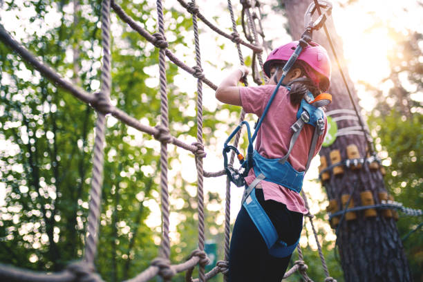 meisje overkomt obstakels in adventure rope park - klimbos stockfoto's en -beelden
