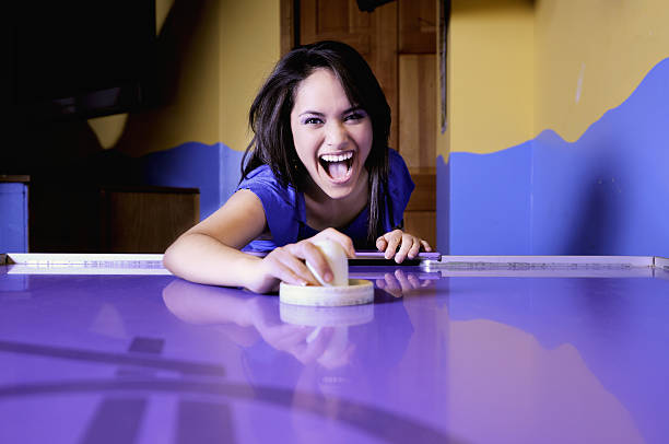Girl playing air hockey in a purple table stock photo