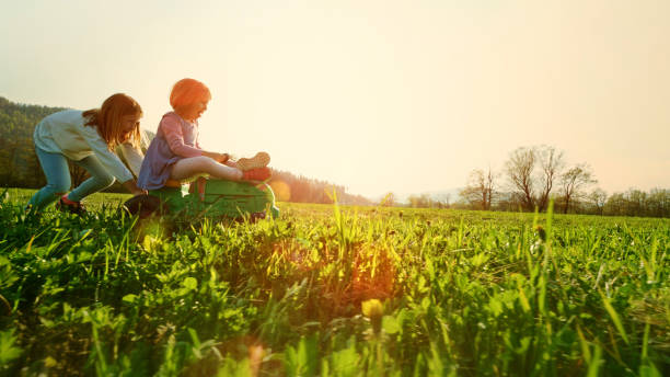 Girl pushing another girl on a toy tractor stock photo