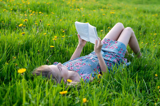 Girl reading a book in the park stock photo