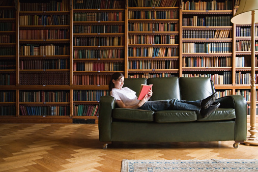 Girl Reading On A Sofa In The Library Stock Photo - Download Image Now -  iStock