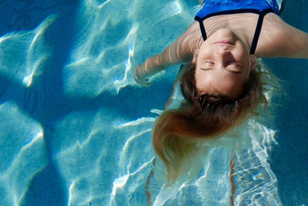 Girl relaxing and floating in a pool (head and shoulders) stock photo