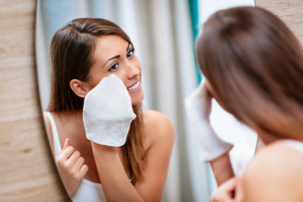 Girl Removing Make Up Beautiful smiling young woman removing make up in front of mirror. washcloth stock pictures, royalty-free photos & images