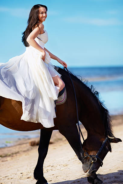 Girl rides along the beach on a horse stock photo
