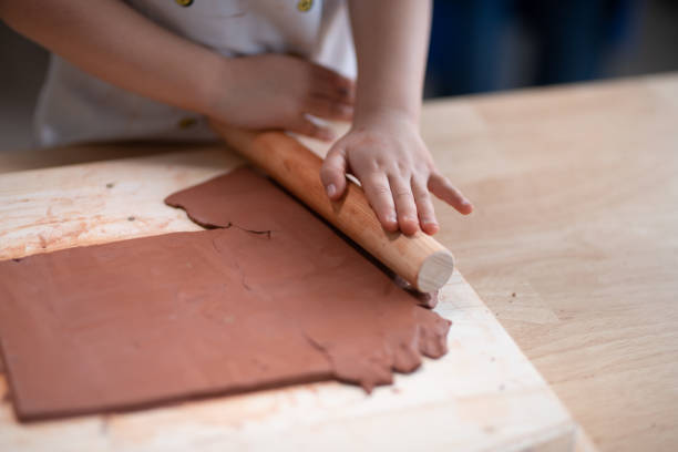 Girl rolling clay in classroom stock photo