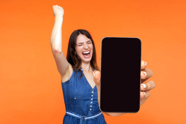 girl screaming with happiness showing mobile advertisement mockup area and celebrating her victory. stock photo