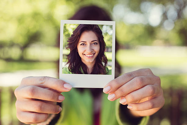 Girl showing instant photo Smiling woman's portrait holding photos stock pictures, royalty-free photos & images
