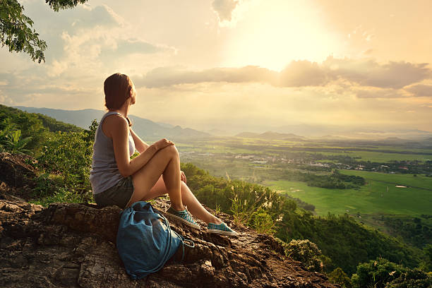 girl sits on edge cliff and looking at sun valley - adventure woman stockfoto's en -beelden
