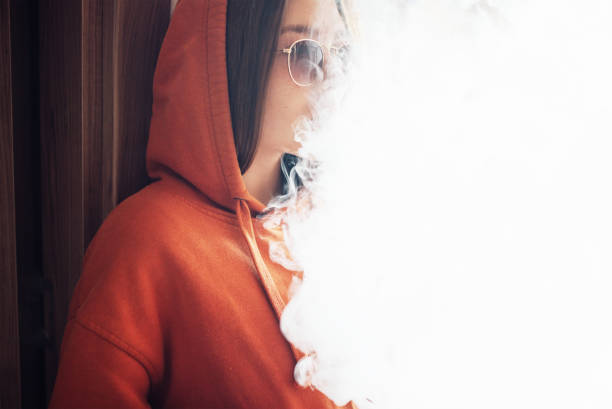 chica fuma vaporizador exhalando una gran cantidad de vapor - cigarrillo electrónico fotografías e imágenes de stock
