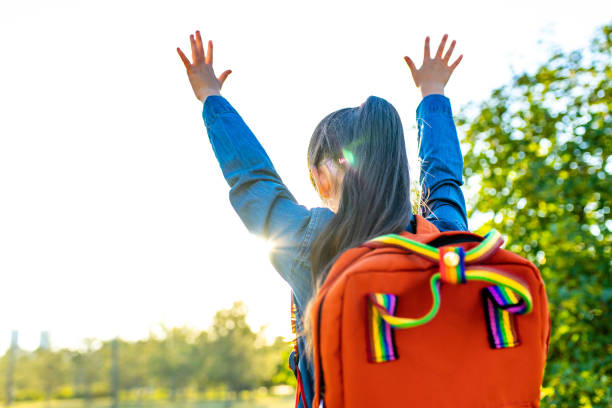 girl student wears backpack outdoors in summer park stock photo
