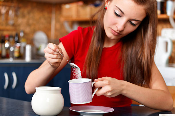 girl sweetening her tea or coffee stock photo