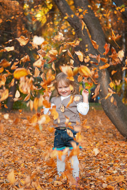 Girl throwing dry leaves stock photo