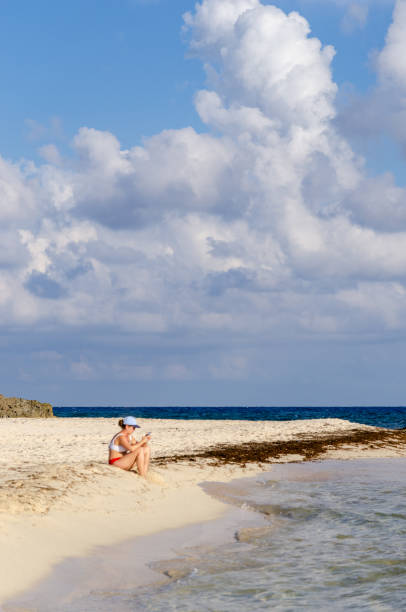 A girl tourist sitting on the caribbean beach enjoying vacation stock photo