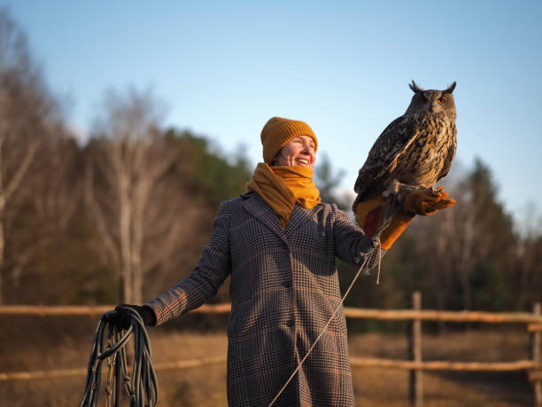 Girl trainer holds an owl on her hand. Autumn background for lettering stock photo