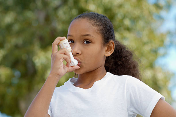 girl (7-9) using inhaler, outdoors - astmatisch stockfoto's en -beelden