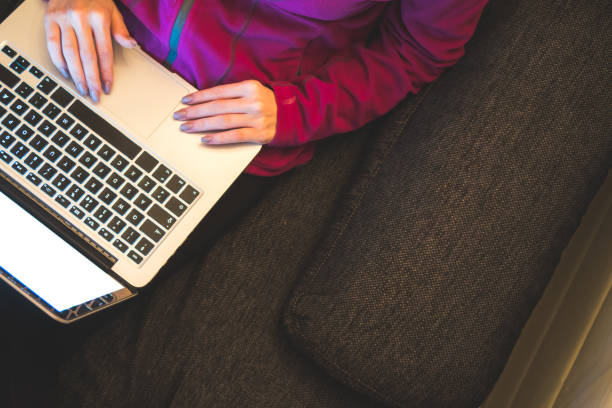 Girl using laptop computer while relaxing in sofa. Copy Space stock photo