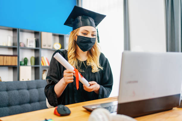 girl wearing graduation gown and cap greeting her relative or friend on video call girl wearing graduation gown and cap greeting her relative or friend on video call online phd programs stock pictures, royalty-free photos & images