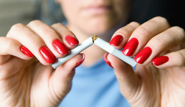 A girl with a beautiful manicure breaks a cigarette. stock photo