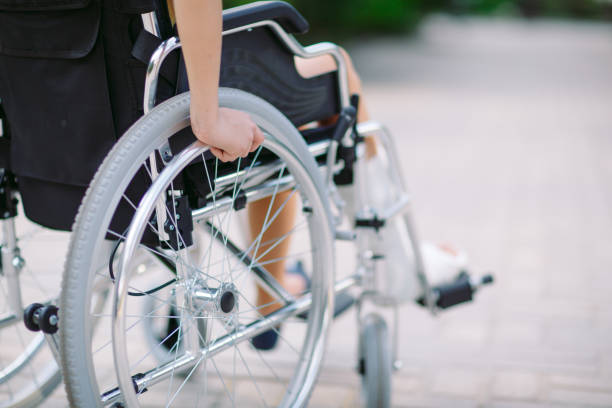 a girl with a broken leg sits in a wheelchair. - wheelchair street imagens e fotografias de stock
