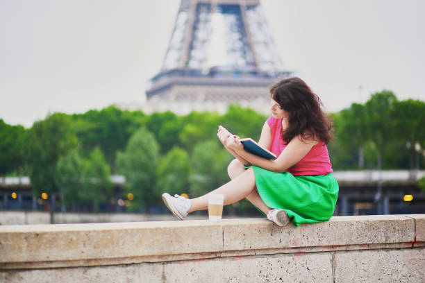 Girl with coffee reading a book near the Eiffel tower stock photo