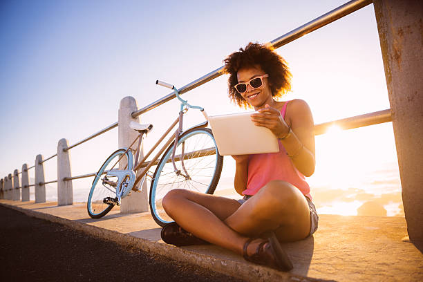 girl with digital tablet near beach - fietsen strand stockfoto's en -beelden